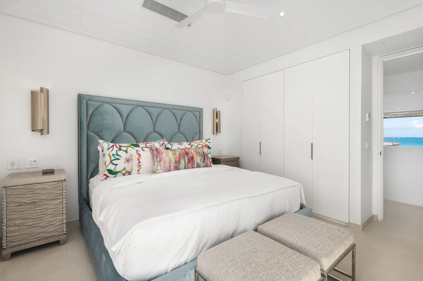 King bed guest room with white closets and an ocean glimpse at Beach Enclave.