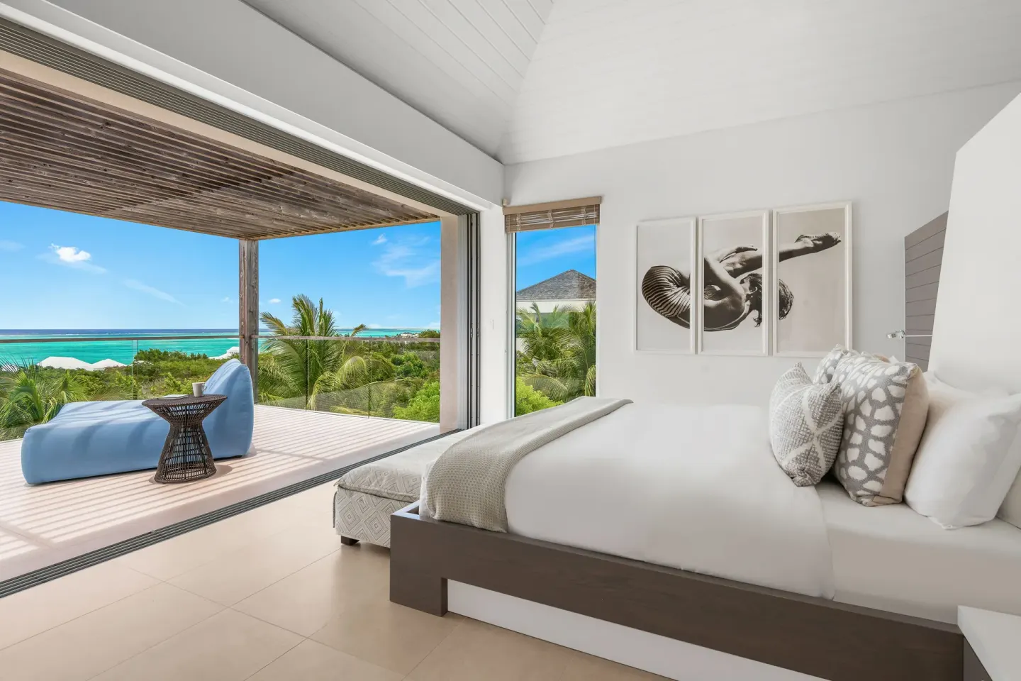 King bedroom opening to a terrace with lounge seating and ocean views at Beach Enclave.
