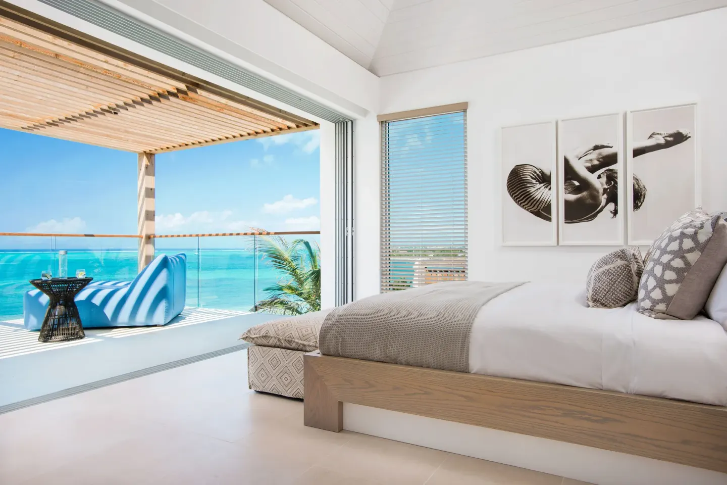 King-bed guest room opening to a blue ocean-view balcony at Beach Enclave.