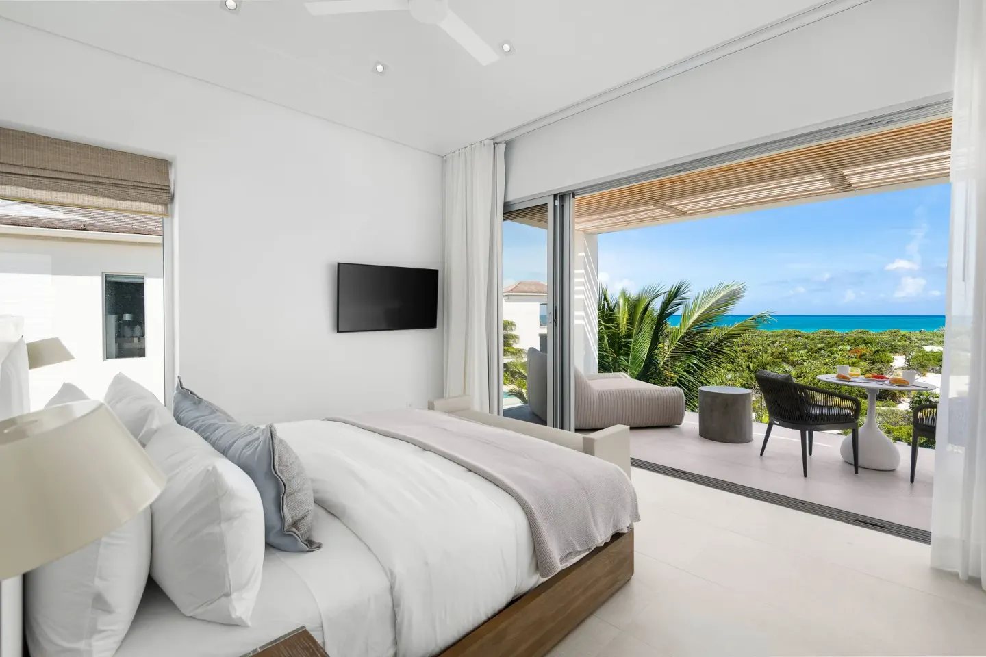 King-bed guest room with terrace seating and ocean view at Beach Enclave.