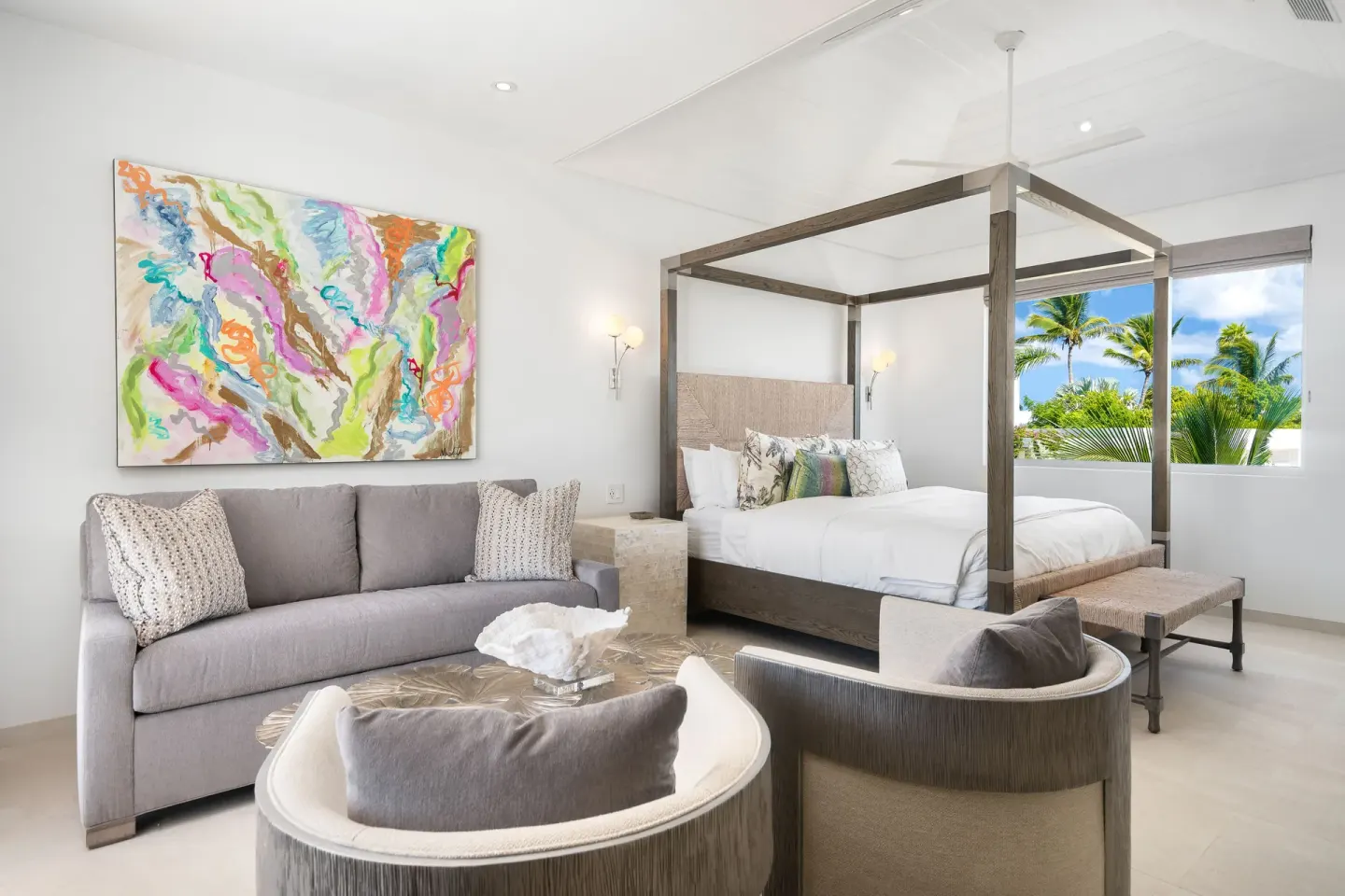 Suite with canopy bed, sofa seating, abstract art, and palm view at Beach Enclave.