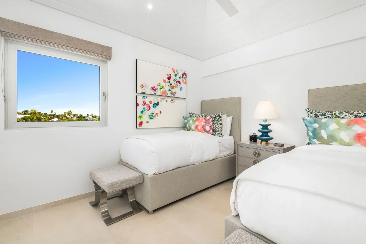 Twin guest room with two beds, colorful art, and a window at Beach Enclave.