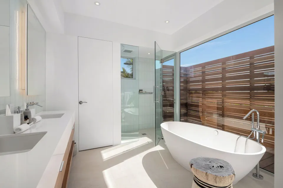 Villa bathroom with freestanding tub, glass shower, and dual sinks at Beach Enclave.