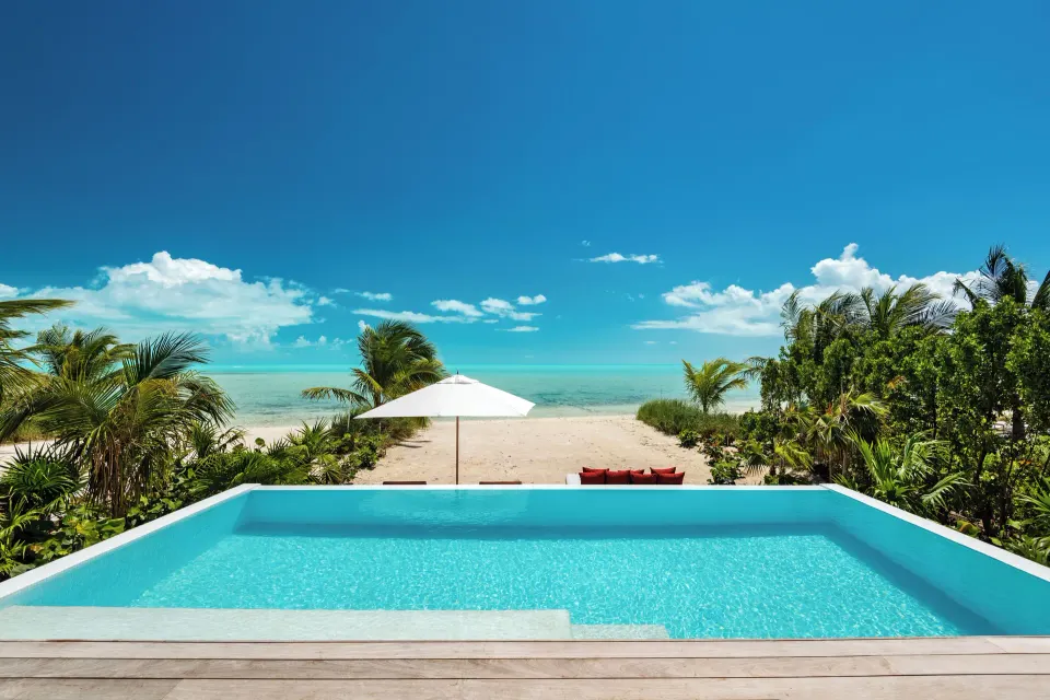 Infinity pool at Beach Enclave facing a sandy beach and bright turquoise ocean.