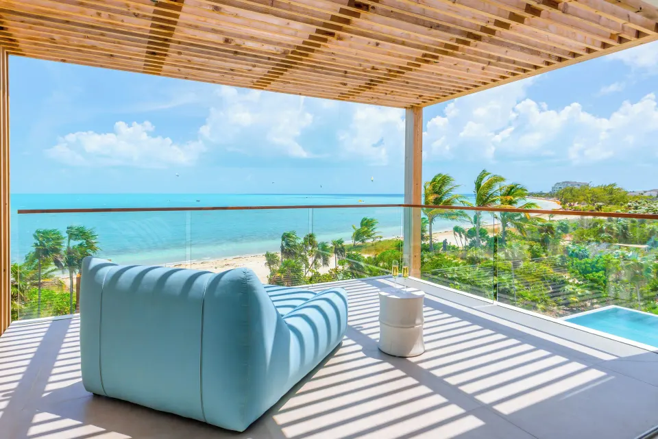 Ocean-facing balcony lounge at Beach Enclave with sofa, glass railing and beach views.