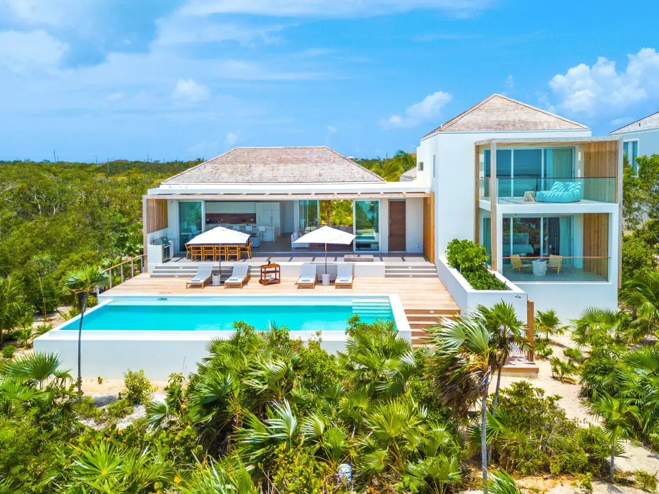 Long Bay villa exterior at Beach Enclave with pool, deck, balconies and tropical landscaping.