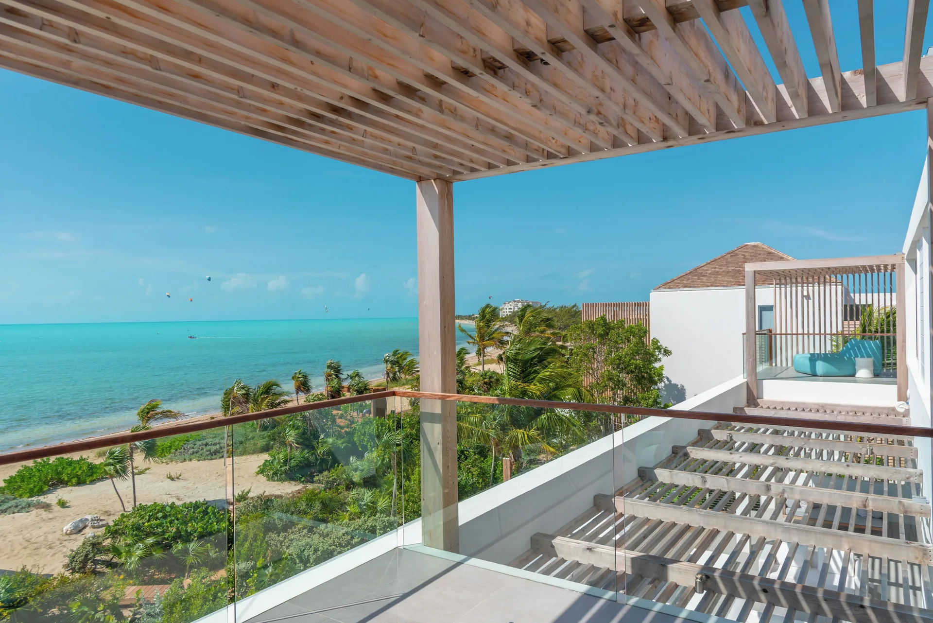 Ocean-view villa terrace with pergola and glass railing at Beach Enclave.