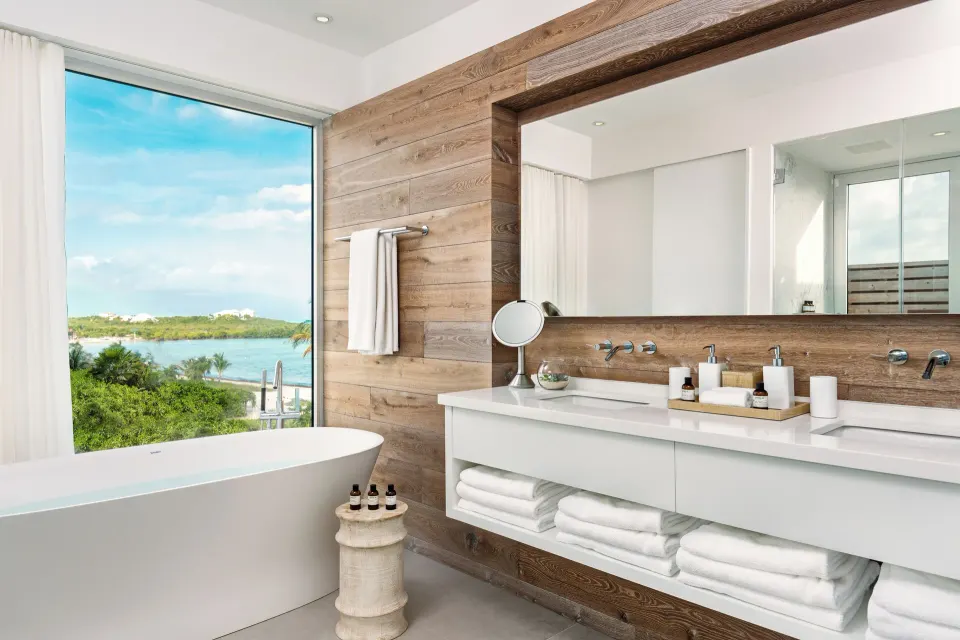 Bathroom with freestanding tub, double vanity, and water view at Beach Enclave.