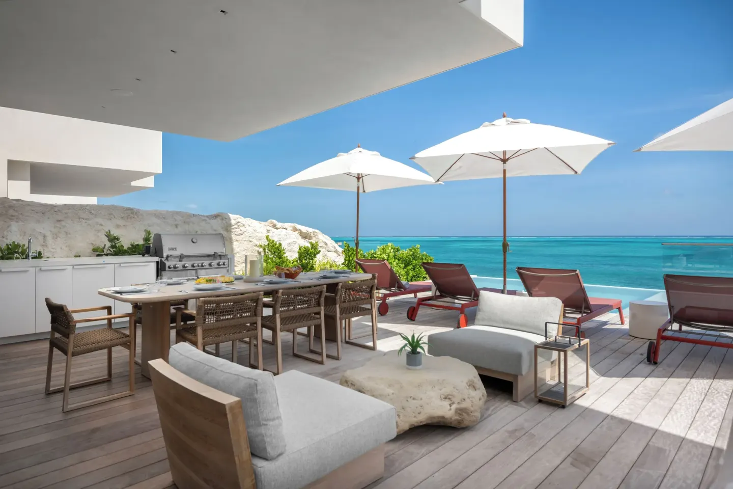 Oceanfront terrace with grill, dining table and loungers at Beach Enclave.