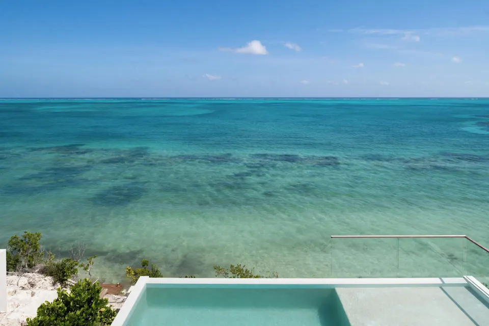 Turquoise ocean view from a glass-edged pool at Beach Enclave.