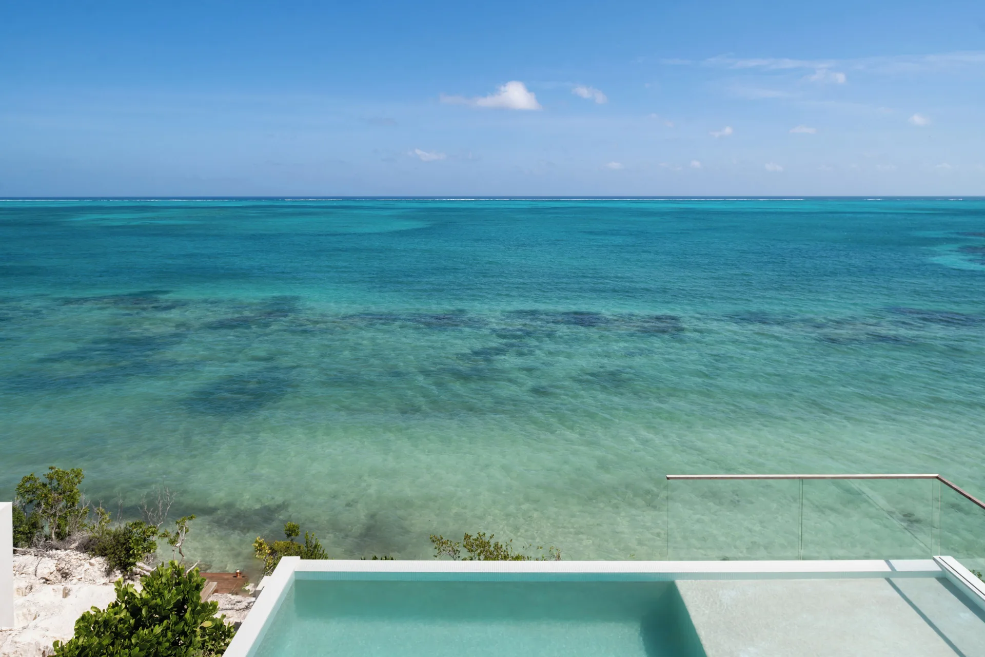 Turquoise ocean view from a glass-edged pool at Beach Enclave.