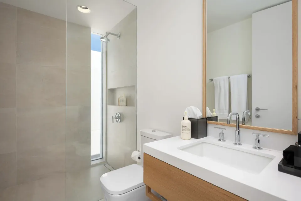 Bathroom with glass shower, vanity, mirror, and white towels at Beach Enclave.