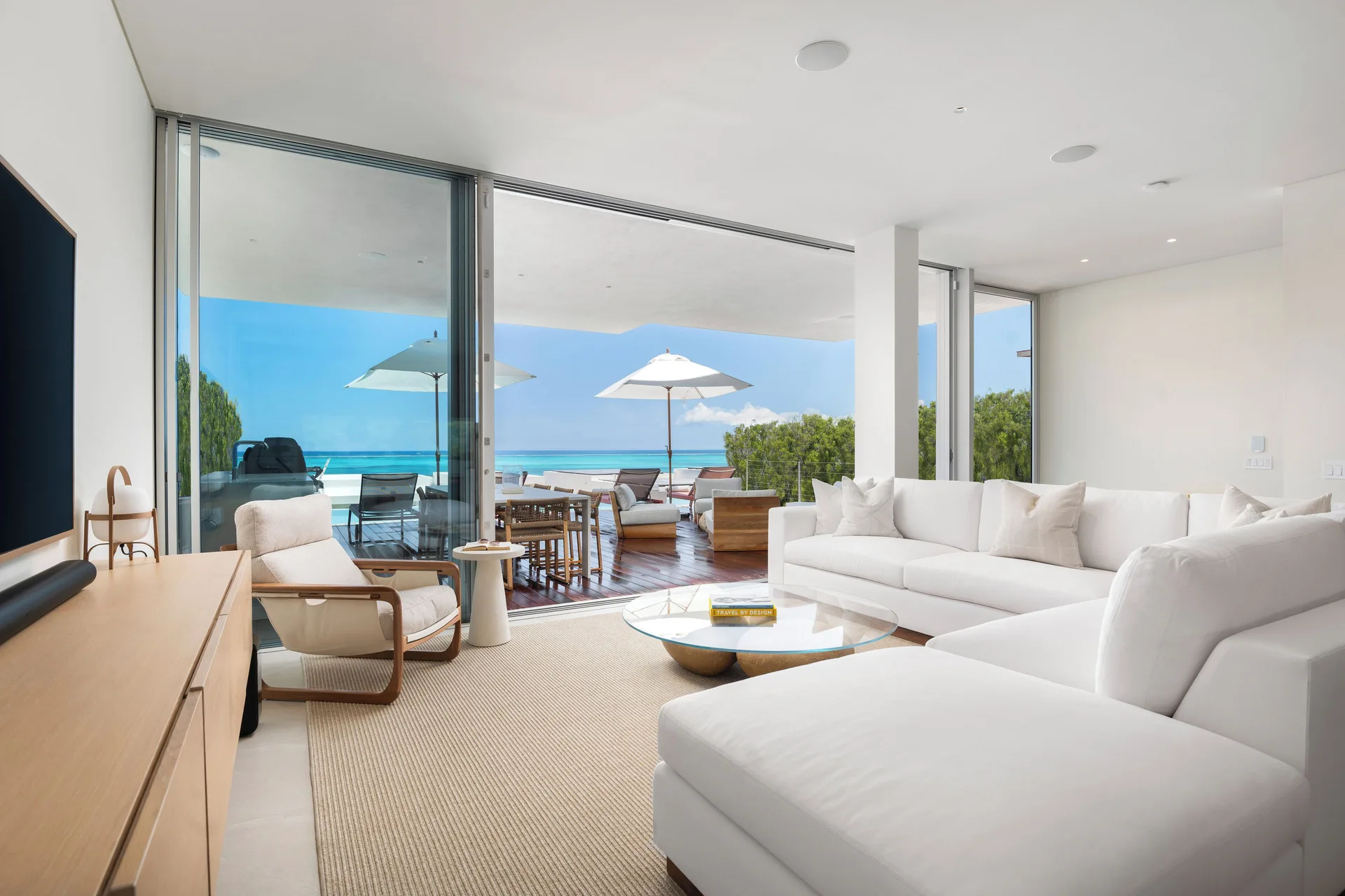 Ocean-view living room with white sectional and terrace at Beach Enclave.