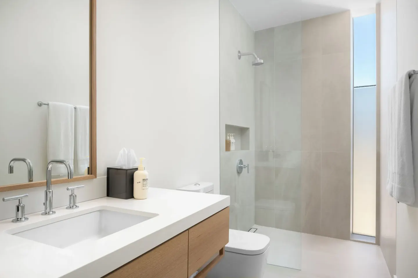 Bathroom at Beach Enclave with a white vanity, mirror, walk-in shower, and towels.