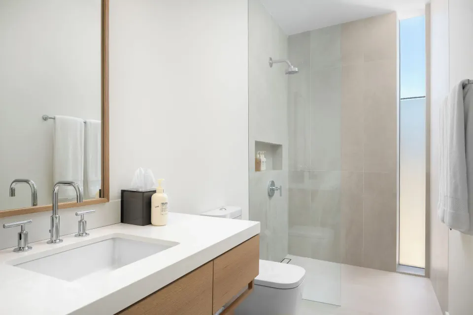 Bathroom at Beach Enclave with a white vanity, mirror, walk-in shower, and towels.