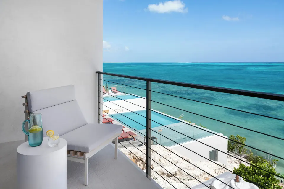 Private balcony at Beach Enclave with a lounge chair, side table, and wide ocean view.