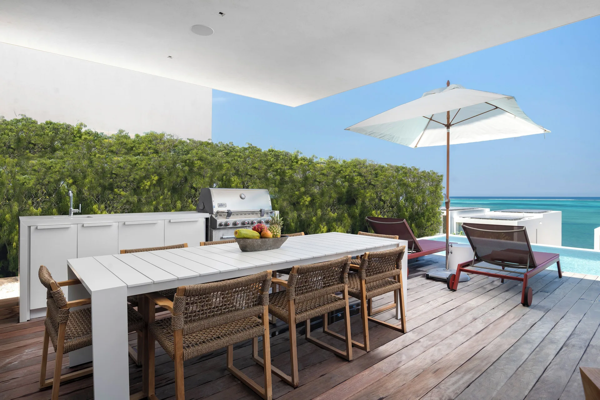 Outdoor dining deck with grill and ocean view at Beach Enclave.