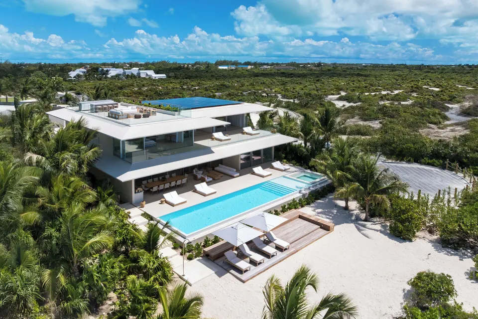 Aerial view of a beachfront villa with pool, terraces, loungers and palms at Beach Enclave.