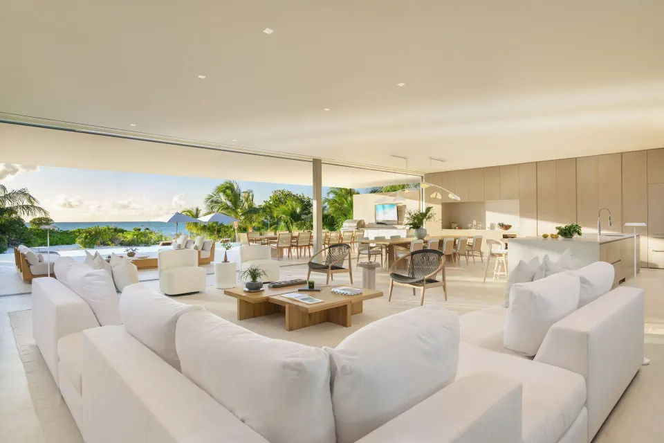 Open-plan living room with sofas, kitchen, dining area and ocean backdrop at Beach Enclave.