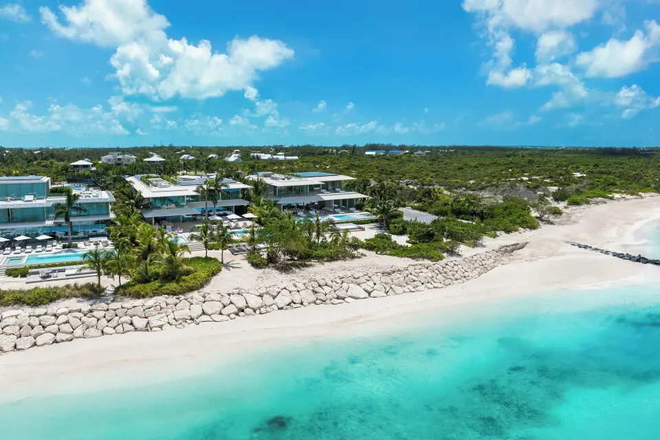 Aerial view of Beach Enclave beachfront villas beside pale sand and turquoise water.