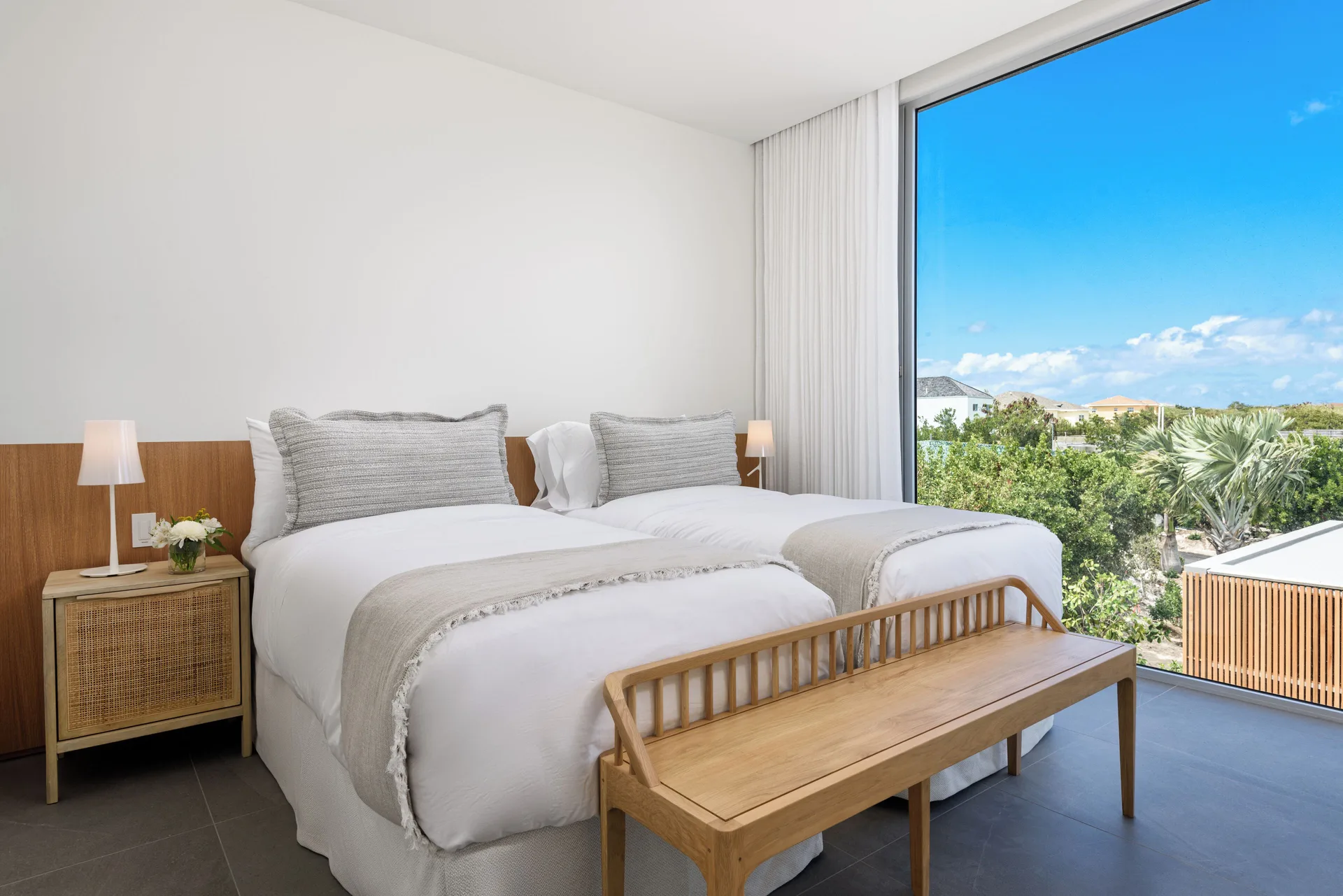 Twin-bed guest room with a large window and greenery view at Beach Enclave.