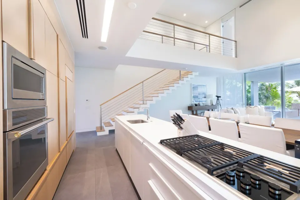 Open kitchen with island, stairs, and living area in a beach house at Beach Enclave.