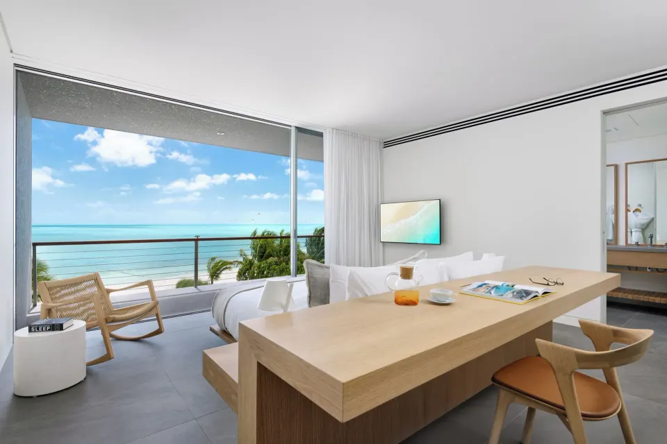 Beachfront bedroom with desk, balcony, and ocean view at Beach Enclave.