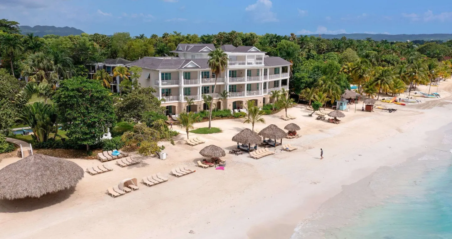 Aerial view of the beach, palms, and beachfront building at Beaches Negril Resort.
