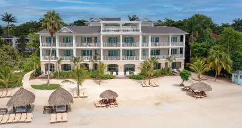 Beachfront resort building with balconies and palapa shade huts at Beaches Negril Resort.