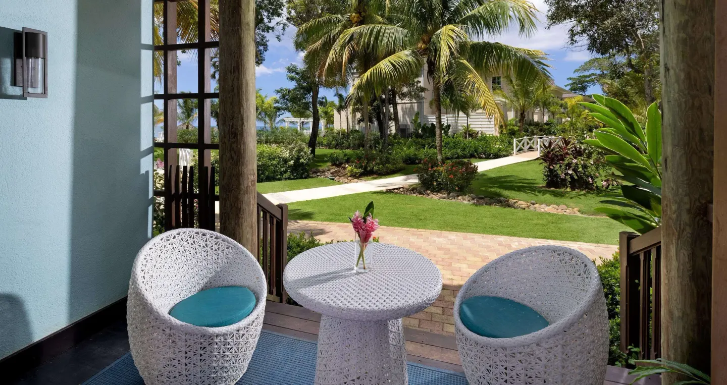 Garden patio seating with white chairs and a round table at Beaches Negril Resort.