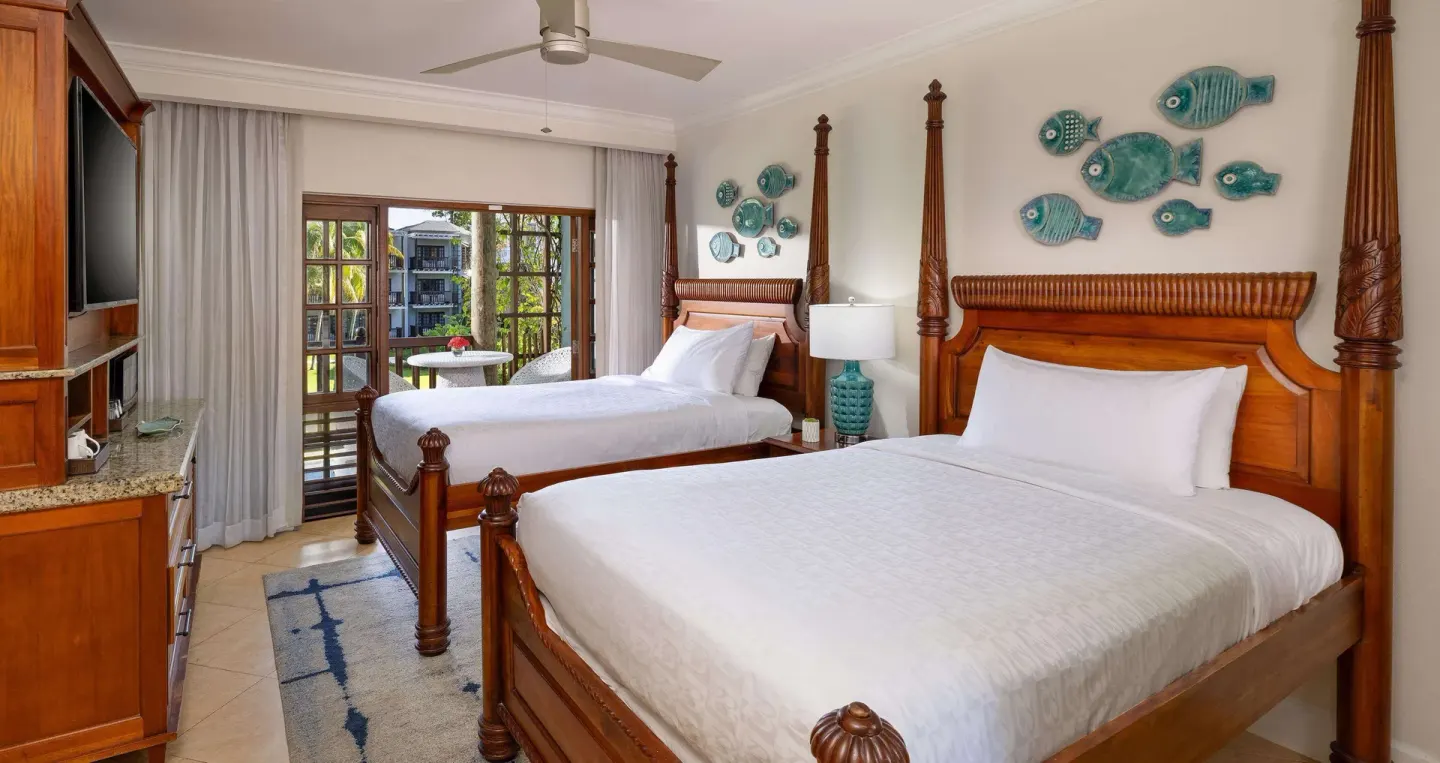 Two poster beds with balcony doors in a guest room at Beaches Negril Resort.