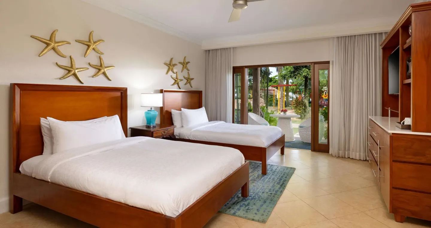 Two-bed guest room with starfish wall decor and patio doors at Beaches Negril Resort.