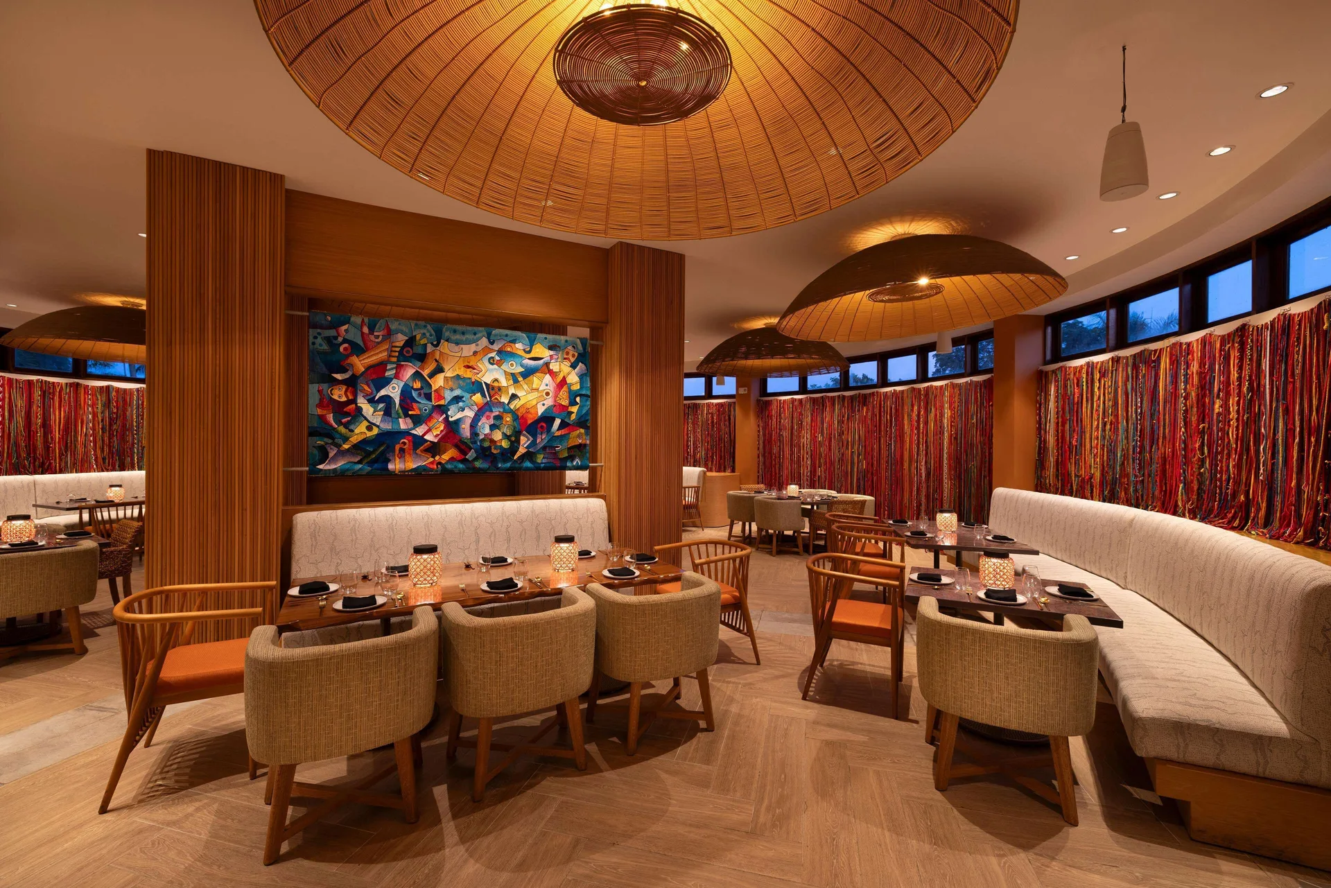 Warm dining room with woven pendant lights and curved banquettes at Beaches Negril Resort.