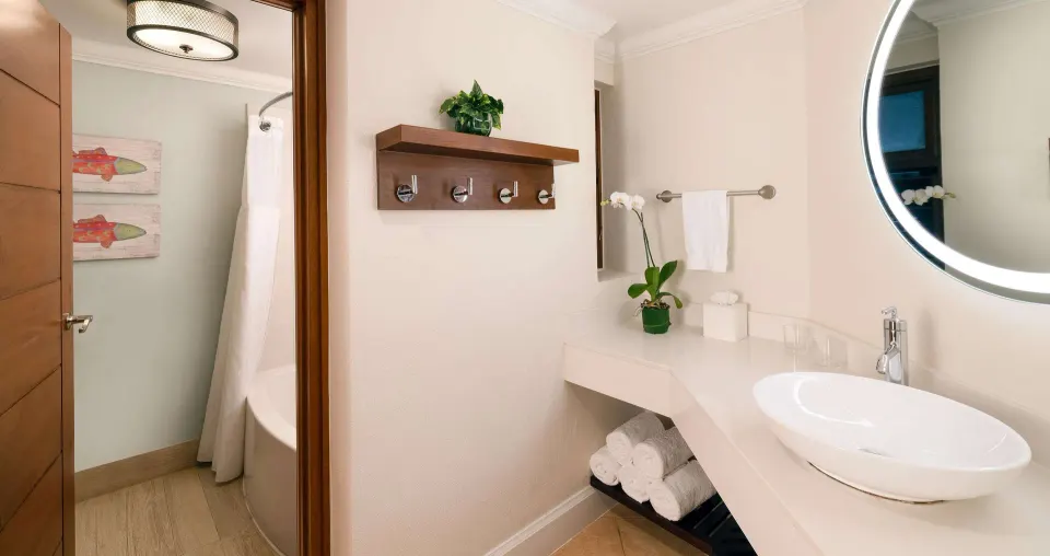 Bathroom vanity in a Grand Suite at Beaches Negril Resort with vessel sink, mirror, towels, and shower beyond.