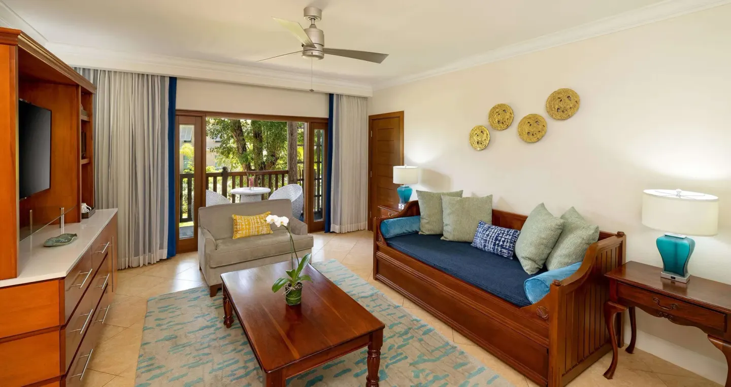 Living area in a Grand Suite at Beaches Negril Resort with daybed, TV, balcony doors, and seating.