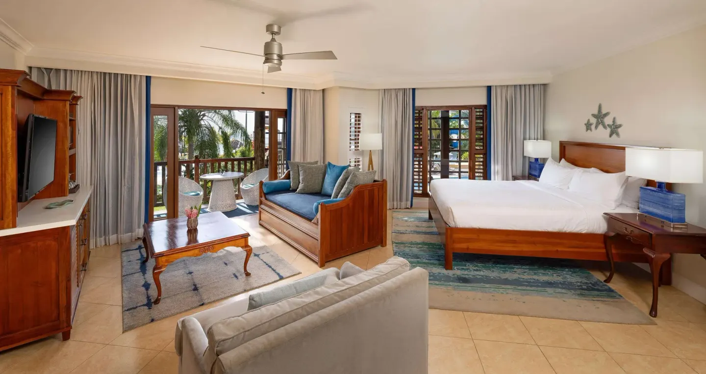 Oceanview junior suite bedroom and sitting area at Beaches Negril Resort with balcony doors open.