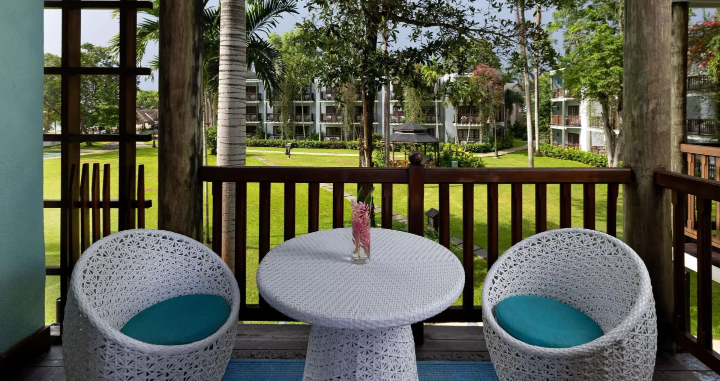 Furnished balcony with white chairs and garden view at Beaches Negril Resort.