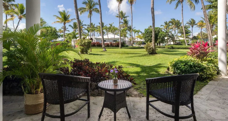 Garden patio at Beaches Turks & Caicos with two chairs, a small table, palms and manicured lawns.