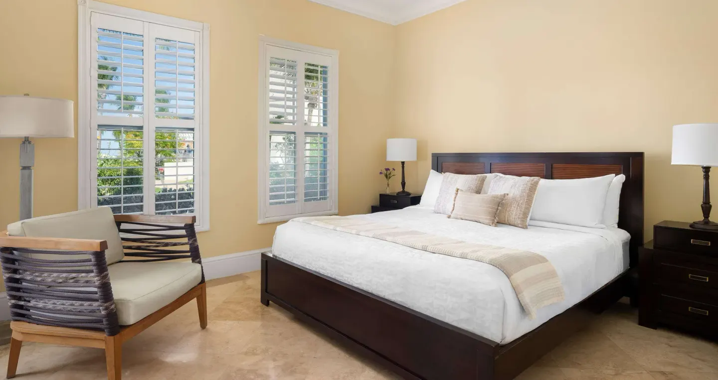 King bedroom with shuttered windows and lounge chair at Beaches Turks & Caicos.