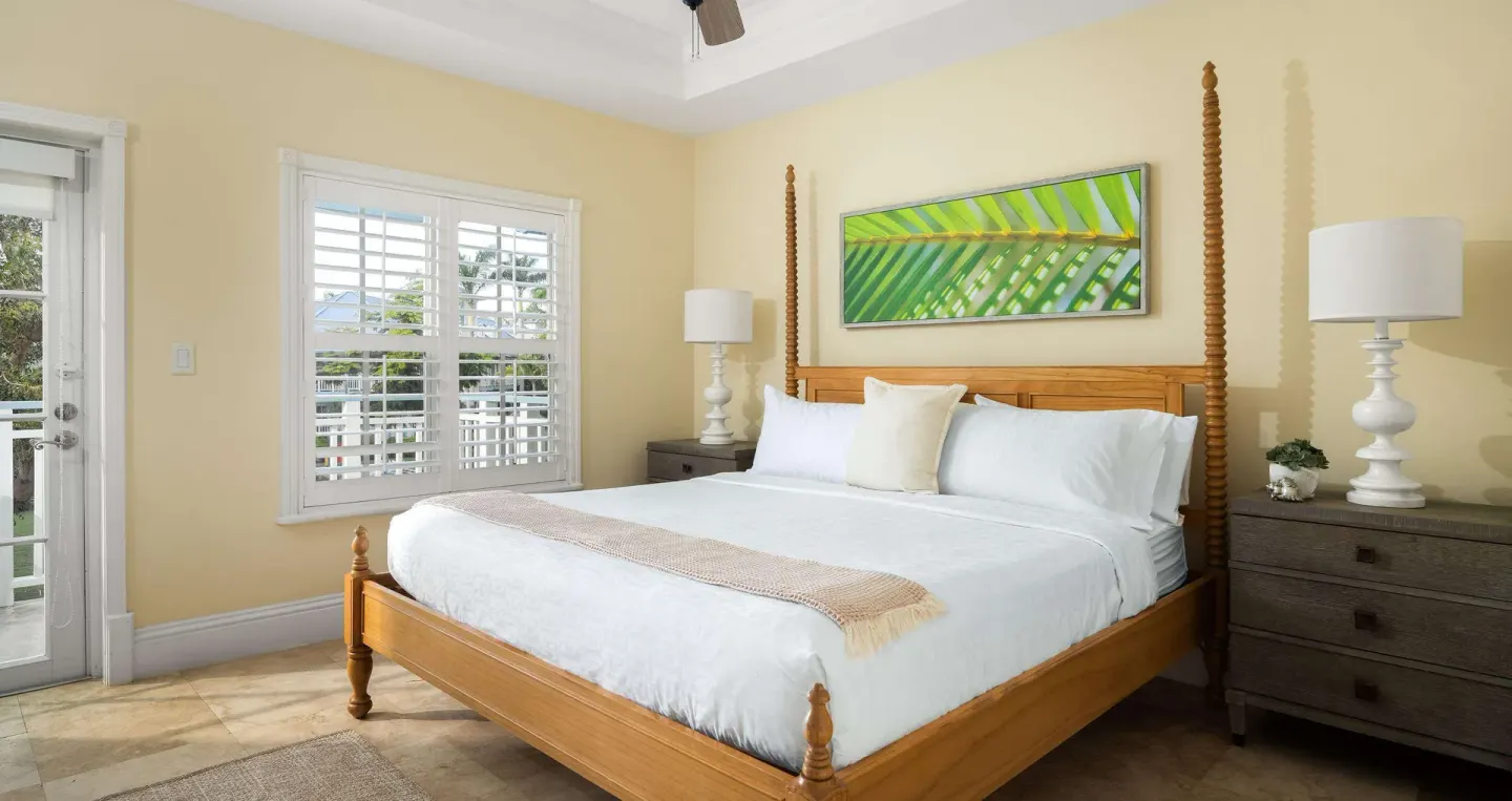 King bed with wood frame and shuttered windows at Beaches Turks & Caicos.
