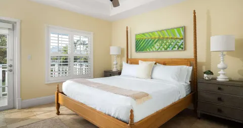 King bed with wood frame and shuttered windows at Beaches Turks & Caicos.