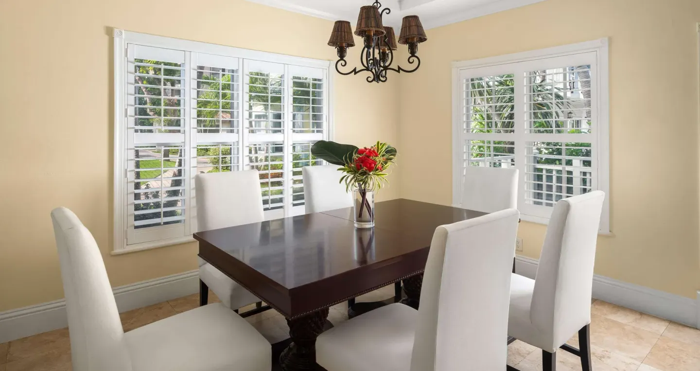 Dining room with white chairs and shuttered windows at Beaches Turks & Caicos.