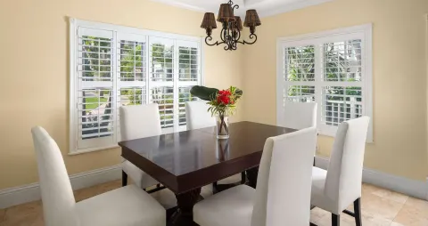 Dining room with white chairs and shuttered windows at Beaches Turks & Caicos.