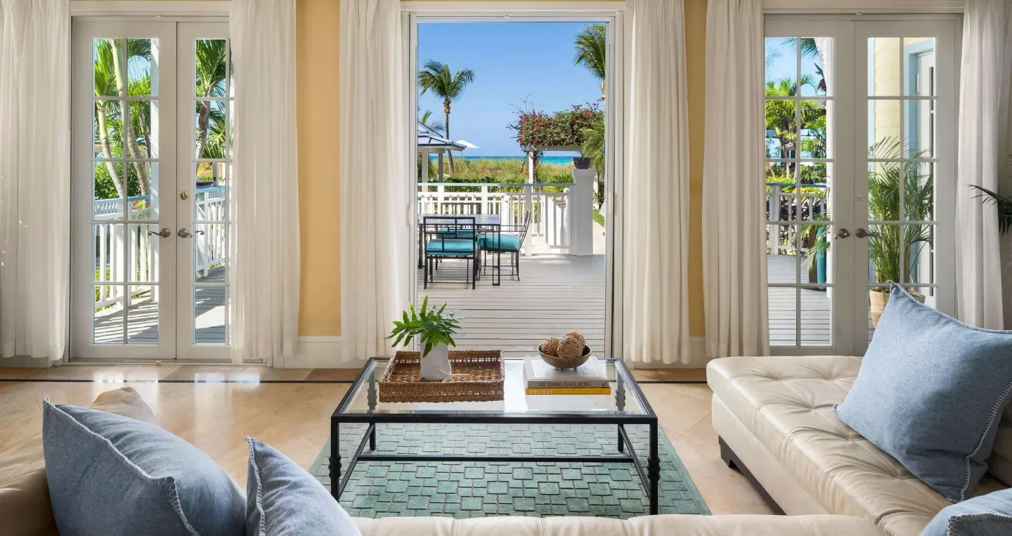 Living room with French doors opening to a pool terrace at Beaches Turks & Caicos.