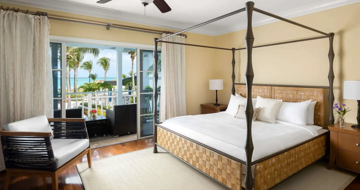 Guest bedroom with four-poster king bed and balcony ocean view at Beaches Turks & Caicos.