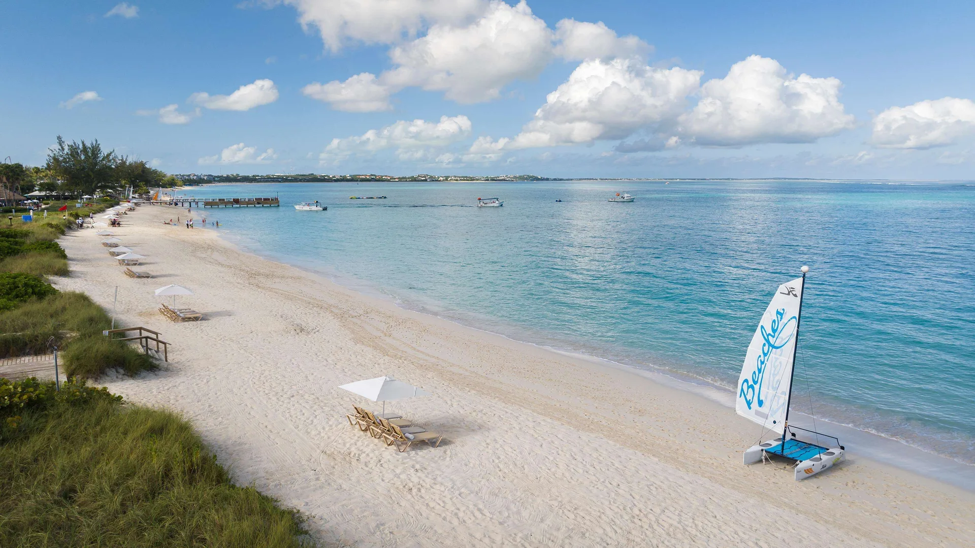 White-sand beach with loungers, umbrellas, and a sailboat at Beaches Turks & Caicos.
