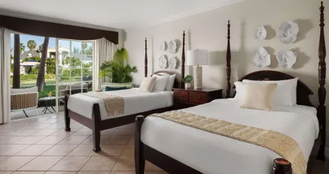 Two beds and garden-facing patio doors in a Luxury Room at Beaches Turks & Caicos.