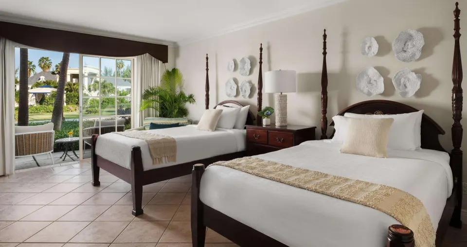 Two beds and garden-facing patio doors in a Luxury Room at Beaches Turks & Caicos.
