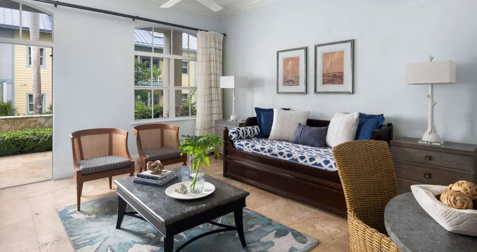 Living area in a Luxury Suite at Beaches Turks & Caicos with daybed, chairs, coffee table and patio access.