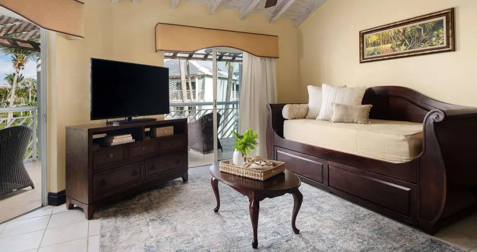 Living area with daybed, TV, and balcony doors at Beaches Turks & Caicos.